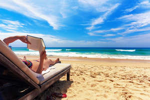 Девушка читает книгу на пляже