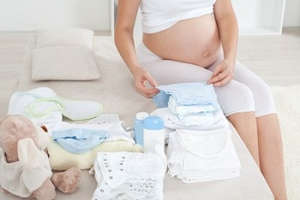 Беременная перебирает детские вещи