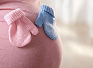 Розовая и голубая варежки на животе беременной