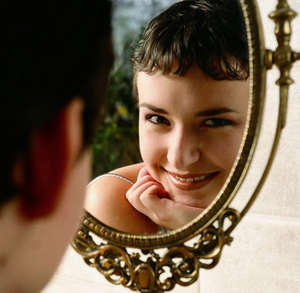 Девушка улыбается перед зеркалом
