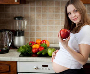 Девушка на кухне держит яблоко