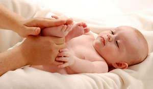 Мама делает массаж ног малышу