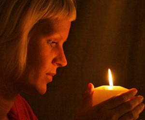 Девушка держит в руках горящую свечу