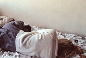 Девушка лежит на кровати лицом к стене