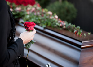 Девушка с розой в руке перед гробом на похоронах