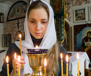 Девушка ставит свечку в церкви