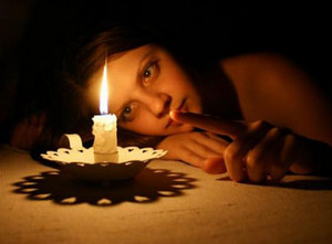 Девушка указывает пальцем на горящую свечу