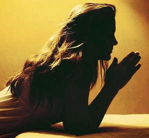 Девушка читает молитву в полутьме