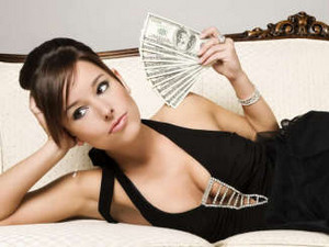 Девушка лежит на диване с пачкой долларов