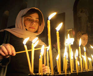 Девушка ставит свечи в церкви