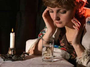 Женщина смотрит на обручальное кольцо в стакане