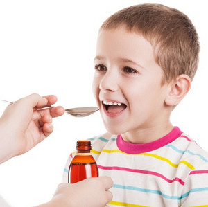 Ребенок пьет лекарство из ложечки