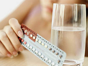 Контрацептивы в руках и стакан воды