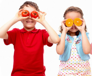 Мальчик и девочка держат фрукты у глаз