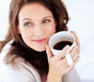 Улыбающаяся женщина держит кружку с кофе