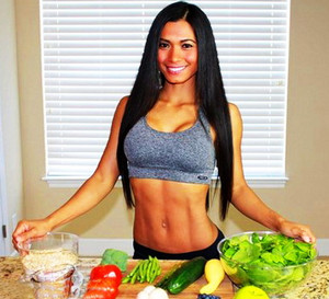 Девушка с красивой спортивной фигурой нарезает овощи