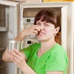 Девушка закрывает нос от запаха из холодильника