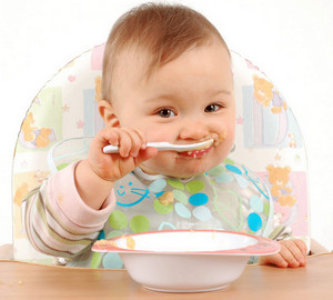Малыш кушает пюре ложечкой из тарелки