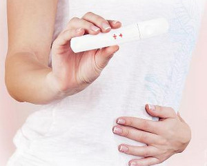 Девушка держит в руках положительный тест на беременность