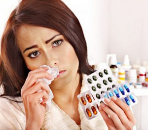 Девушка с насморком держит в руках разные таблетки