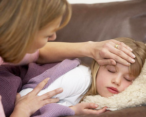 Мама меряет рукой температуру у дочки