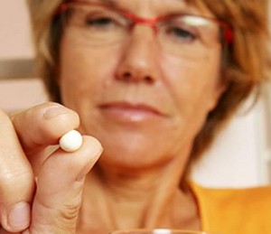 Женщина держит в руках одну таблетку