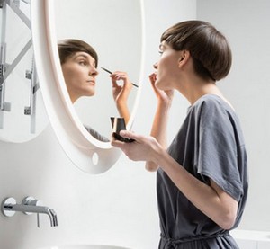 Девушка наносит макияж перед зеркалом