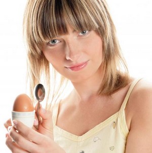 Девушка держит крутое яйцо в руке
