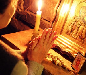 Женщина читает молитву перед иконами