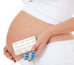 Беременная девушка держит таблетки в руках