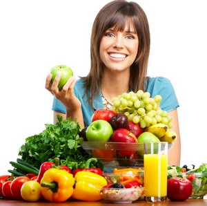 Девушка сидит за столом с овощами и фруктами