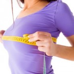 Девушка в фиолетовой футболке измеряет грудь сантиметром