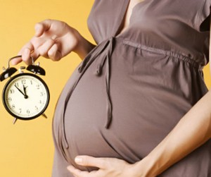 Беременная девушка держит в руках часы