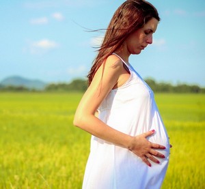 Беременная девушка гуляет в поле
