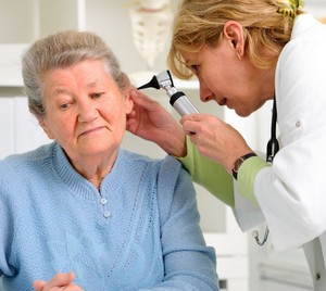 Доктор осматривает ушной проход у пожилой женщины