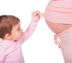 Ребенок смотрит на живот беременной мамы