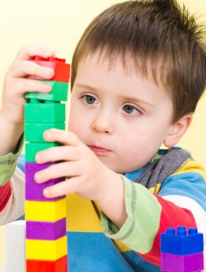 Мальчик строит башню из кубиков лего