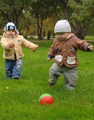Малыши играют в мяч на траве