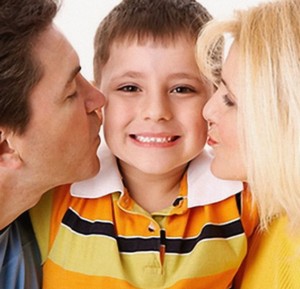 Родители целуют сына в щеки