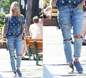 Девушка идет по улице в джинсах с прорезями