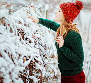 Девушка в яркой одежде стоит у зимнего куста