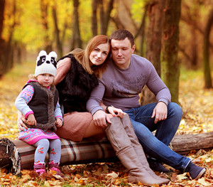 Родители с ребенком сидят на бревне в лесу