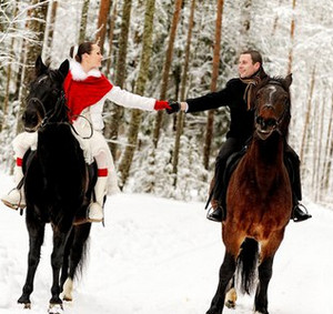 Влюбленные катаются на лошадях по зимнему лесу