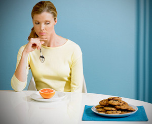 Девушка с грустью смотрит на тарелку с печеньем