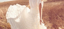 Девушка в длинном белом платье стоит в поле
