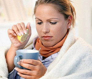 Простуженная девушка пьет чай с лимоном