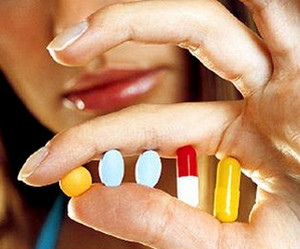 Разные таблетки в руке у женщины