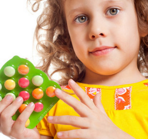 Девочка держит в руках цветные таблетки