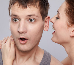 Женщина шепчет на ухо мужчине