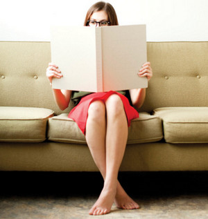 Женщина сидит на диване и читает книгу